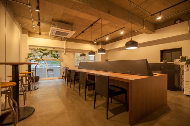 1階ワークラウンジ。24時間利用可能なWi-Fi・家具・複合機等完備のワークスペースです。利用には月額費用が必要です。