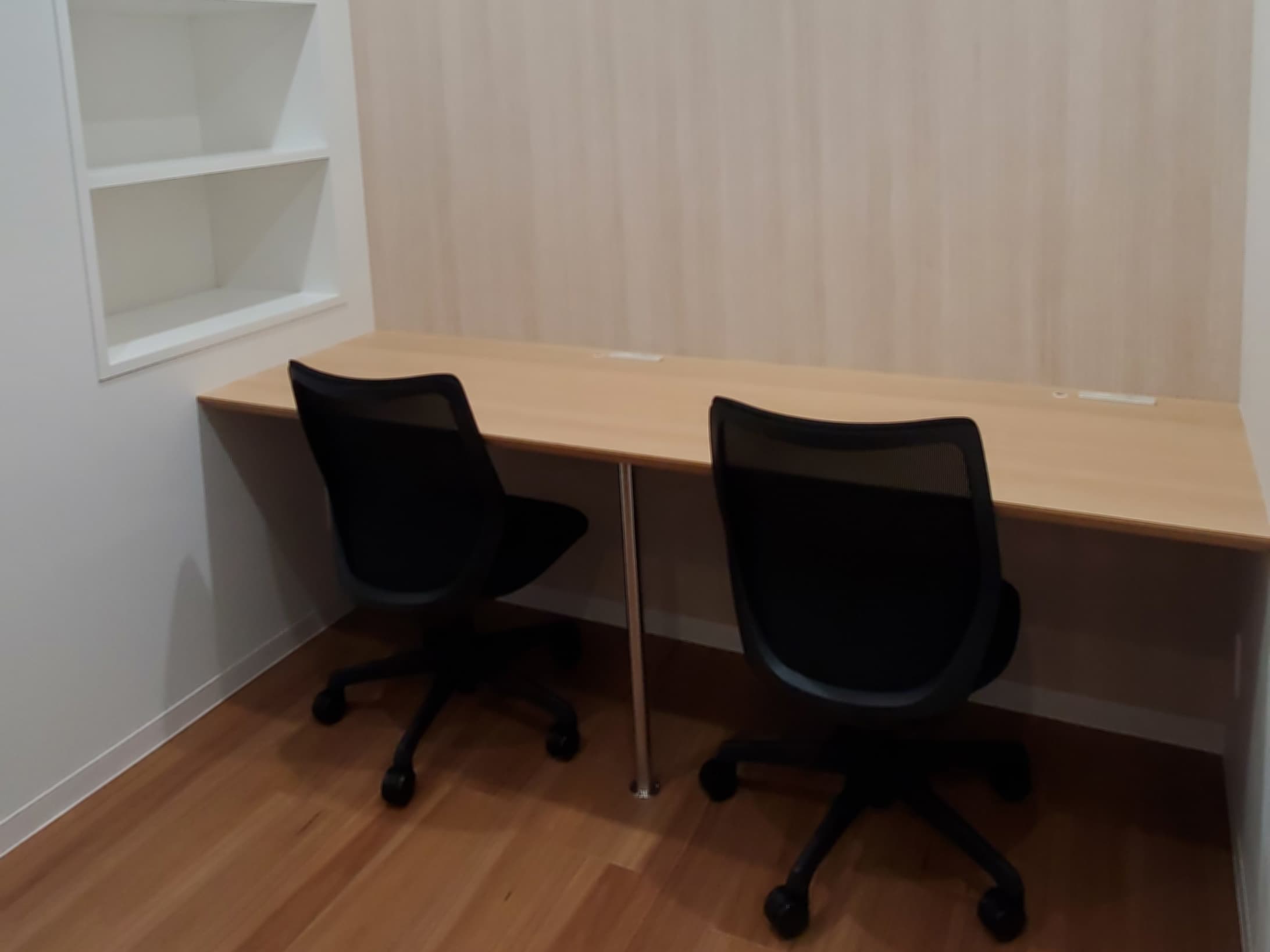 個室_机、椅子が備え付けられています。白と木目調のシンプルなデザインの部屋です。