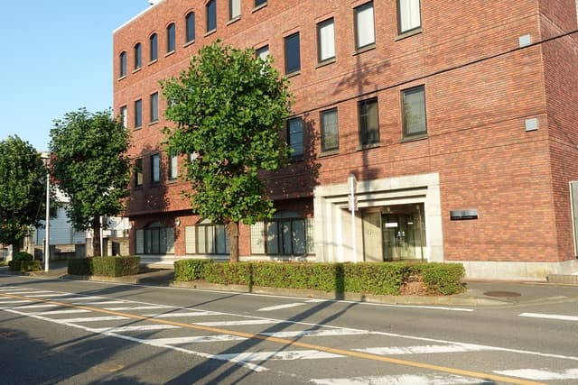 建物外観。本庄駅から徒歩7分の場所にあり、地上4階建てでレンガ造りのビルです。