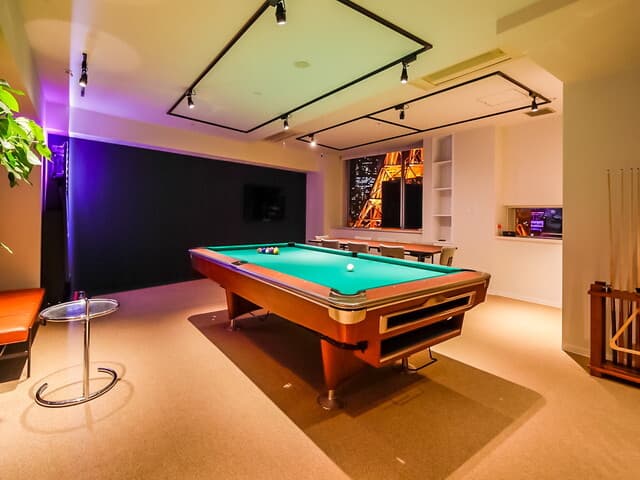共用部_PLAY LOUNGE。窓から東京タワーを臨み、ダーツやビリヤード台がある時間貸し共有スペースです。飲食も可能で、社内イベントなどに利用できます。